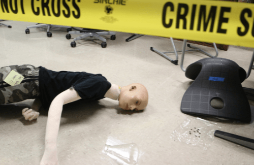 mock crime scene with tape encircling mannequin "victim"